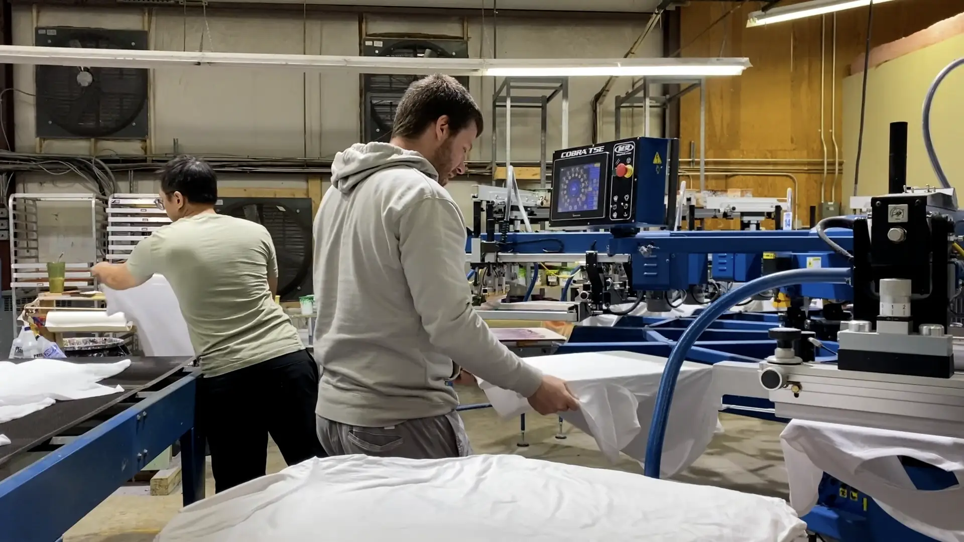 Production team members loading shirts on to the press
